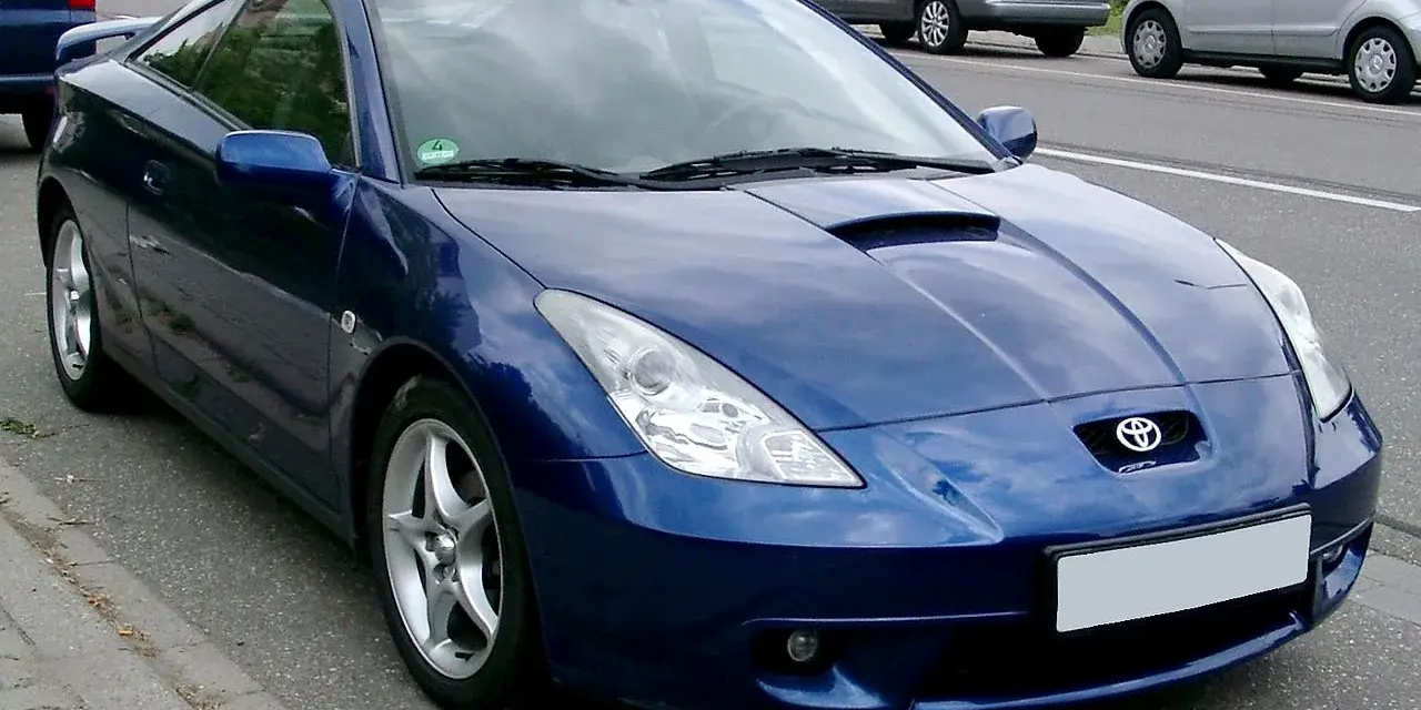 Błękitna Toyota Celica, jeden z najpiękniejszych aut, parkuje na poboczu drogi.