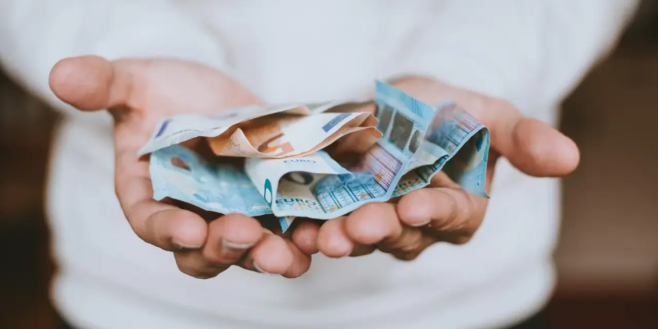 Dłonie trzymające banknoty euro, symbolizujące opłatę za pełnomocnictwo.