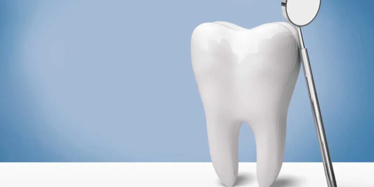 Biały ząb i lusterko dentystyczne. Pamiętaj, po piaskowaniu zębów nie wolno nic jeść przez godzinę.