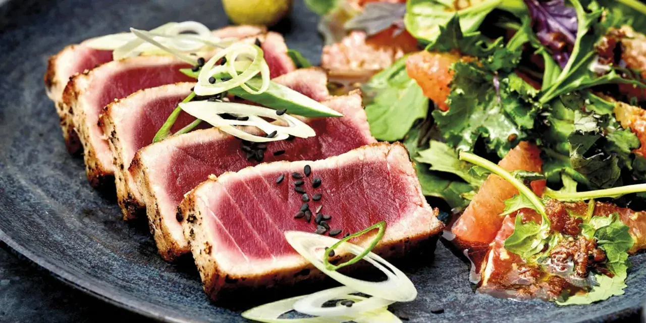 Tataki de atún perfectamente sellado, servido con una ensalada fresca de cítricos y hojas verdes.