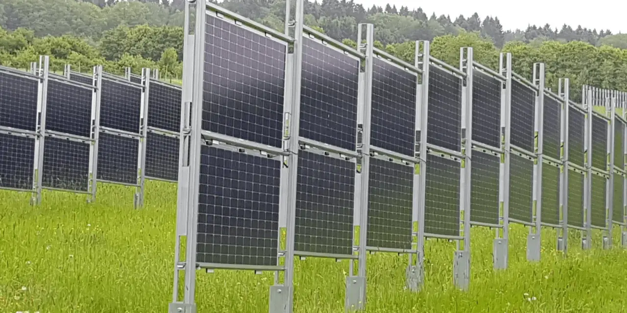 Rzędy wydajnych paneli fotowoltaicznych na tle zielonego lasu. Instalacja na łące, gotowa do produkcji czystej energii.