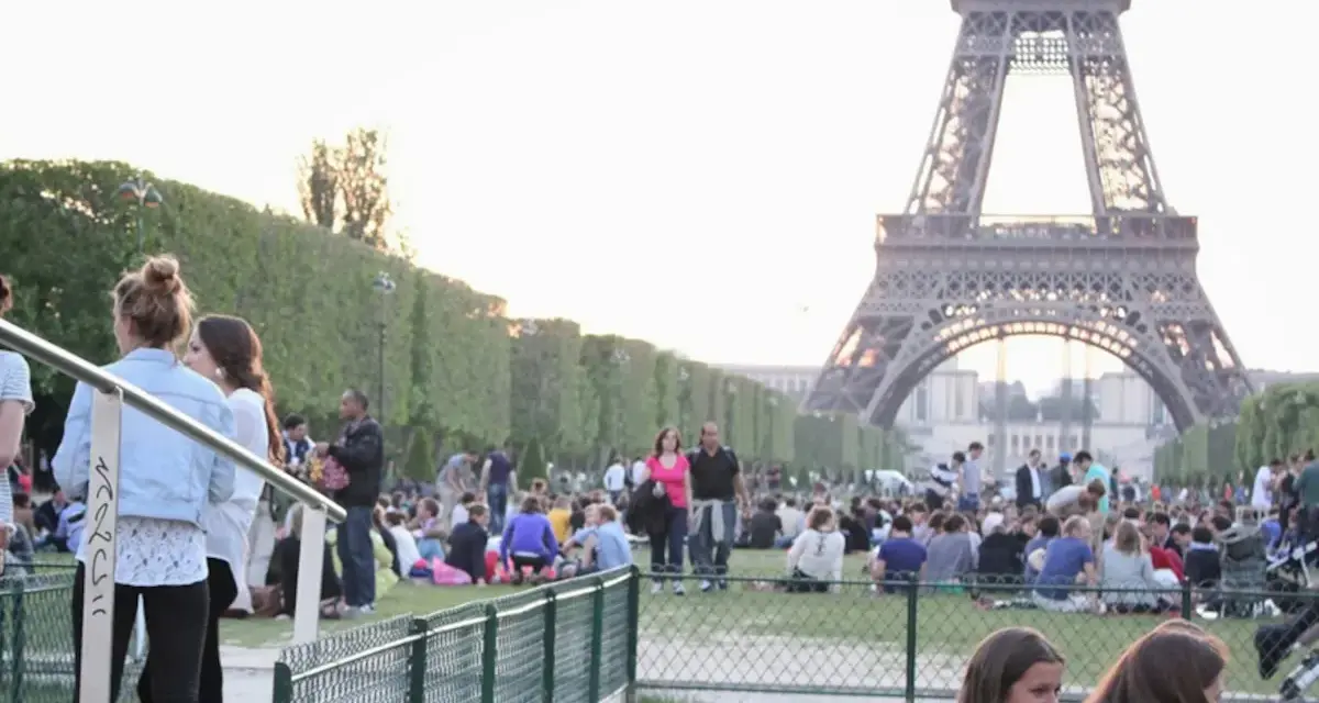 Gente disfrutando de un día soleado en París, con la Torre Eiffel de fondo. Un momento perfecto para la bise en France.