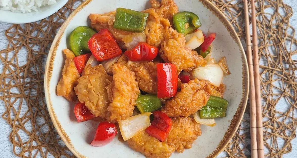 Delicioso pollo agridulce con pimientos rojos y verdes, y cebolla. Un plato vibrante y sabroso, listo para disfrutar.