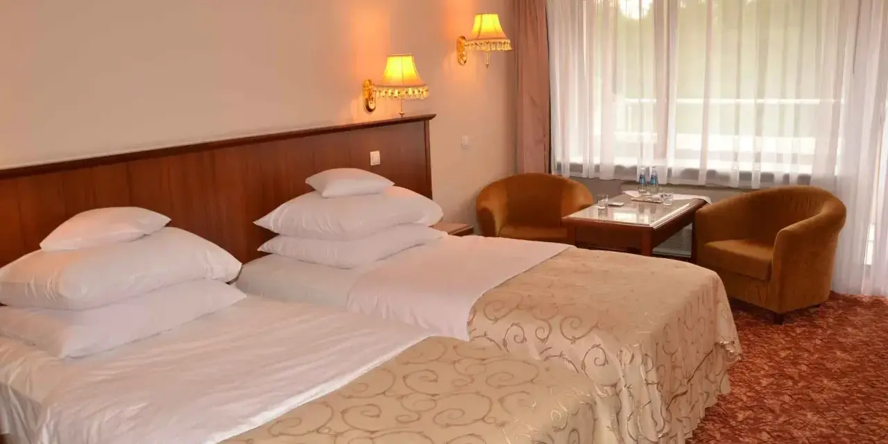 Przytulne hotel Gołębiewski pokoje z dwoma wygodnymi łóżkami, stolikiem i dwoma fotelami.