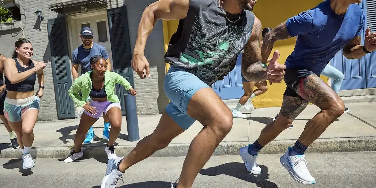 Grupa biegaczy w letnich strojach pokonuje miejską trasę. To inspiracja, jak przygotować się do maratonu, czerpiąc radość z ruchu.
