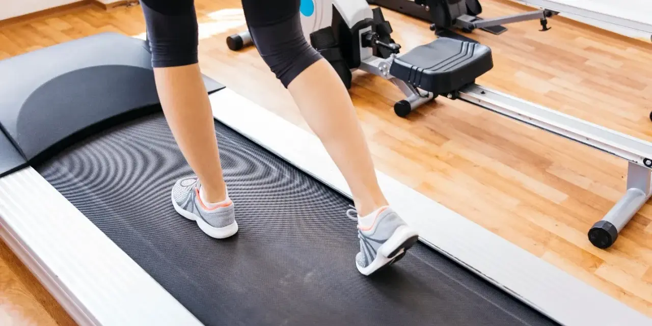 Gambe di donna che cammina su un tapirulan, in allenamento per la gravidanza.