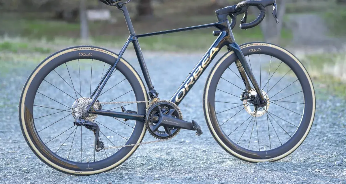 A dark blue Orbea Orca road bike with gold lettering, Ultegra components, and deep-dish wheels. This is a great bike for an Orbea Orca review.
