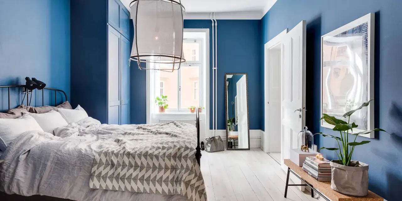 Accogliente camera da letto blu con letto comodo, armadio scuro e specchio a figura intera.