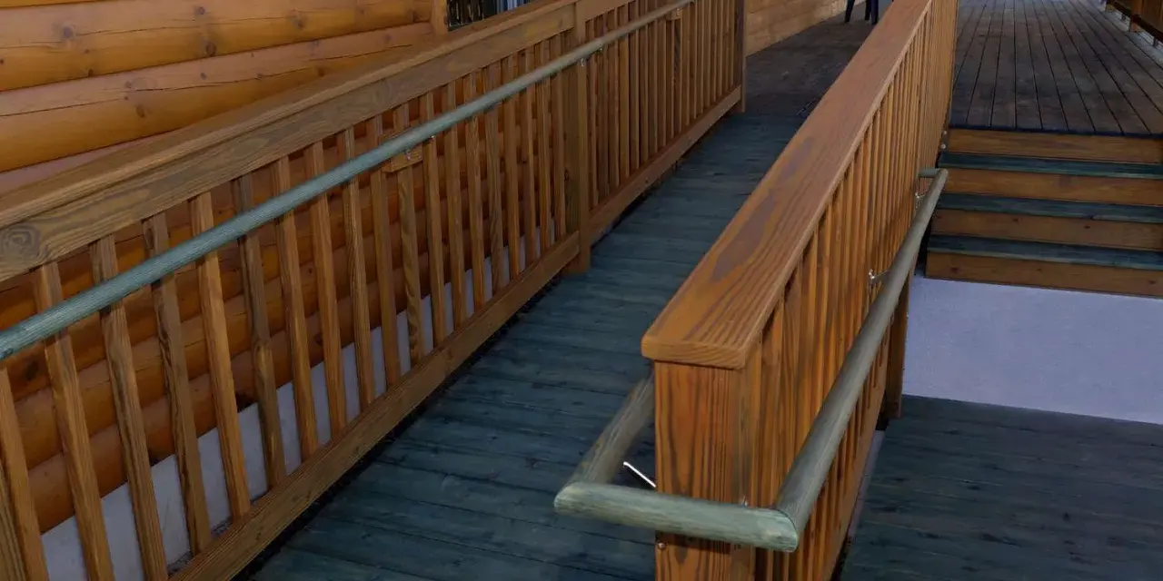 A wooden wheelchair ramp with railings curves around a log cabin. This shows how to build a wheelchair ramp for accessibility.