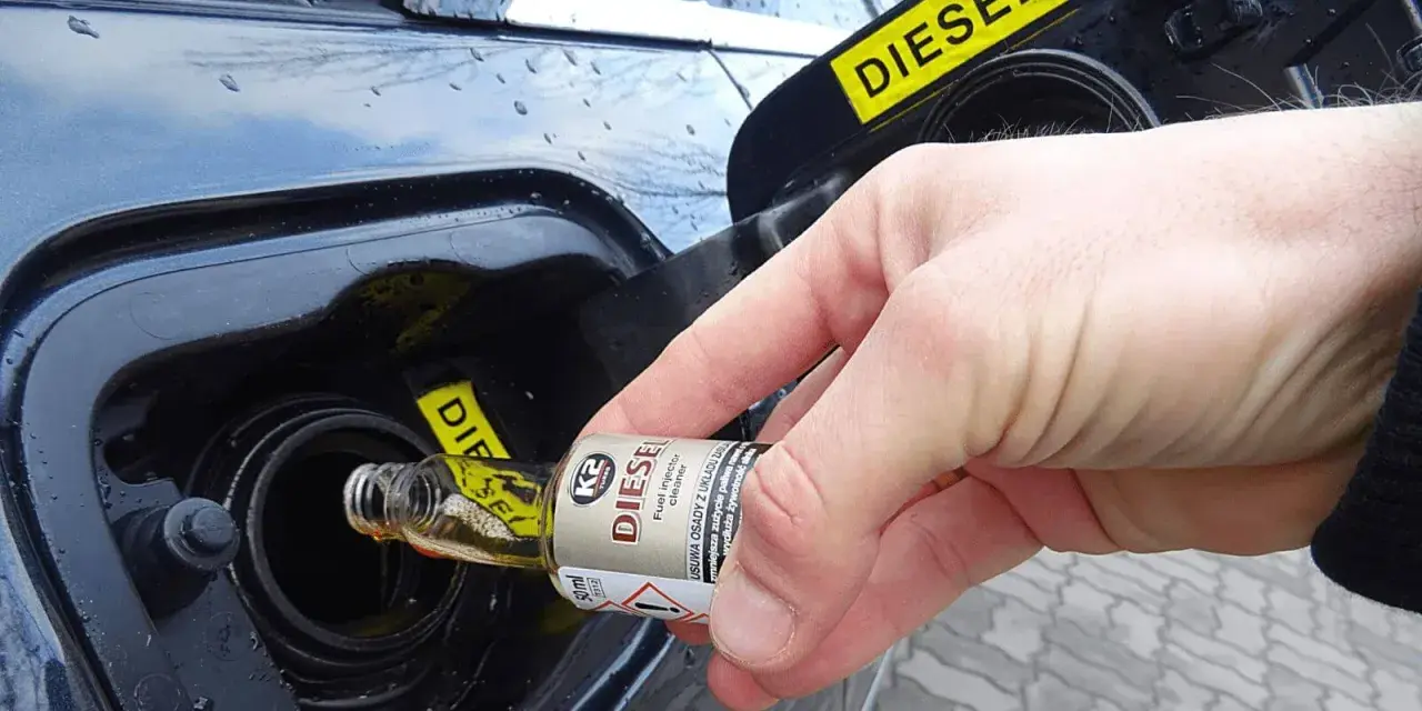 Dłoń wlewa dodatek do benzyny do baku samochodu z napisem DIESEL.