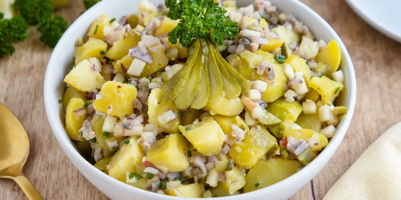 Schlesischer Kartoffelsalat mit Gurken, Zwiebeln und Petersilie, appetitlich garniert.