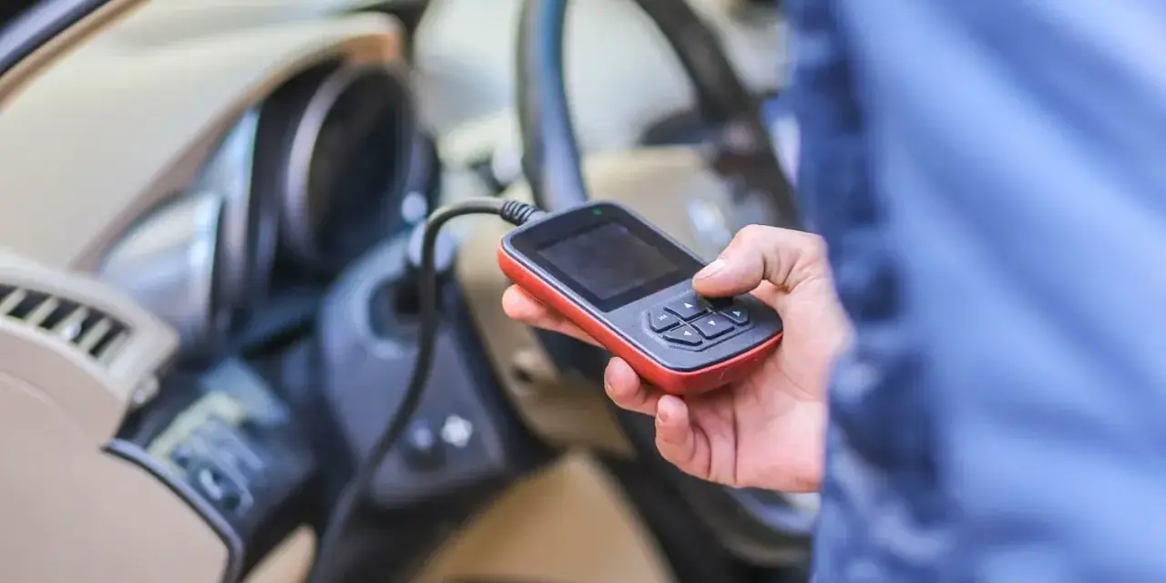 Diagnostyka Renault, być może błąd DTC B1267. Ręka trzyma urządzenie diagnostyczne podłączone do samochodu.