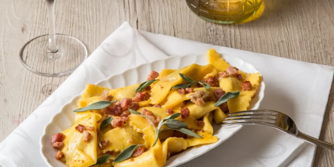 Piatto di casoncelli alla bergamasca conditi con burro, salvia e pancetta croccante.