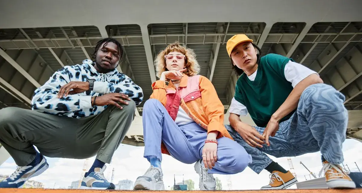 Tre giovani con look urbani, ognuno con le sue sneakers, mostrano cosa sono le sneakers: calzature comode e alla moda per ogni stile.