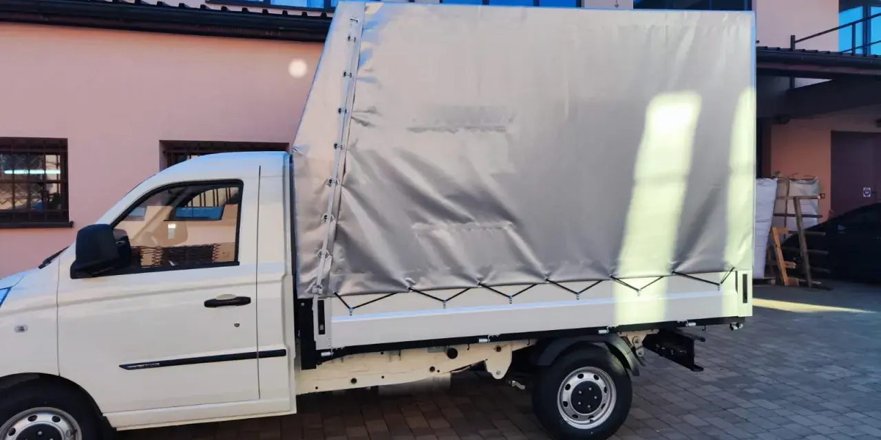 Biały samochód ciężarowy do 2,5 tony z plandeką gotowy do transportu towarów.