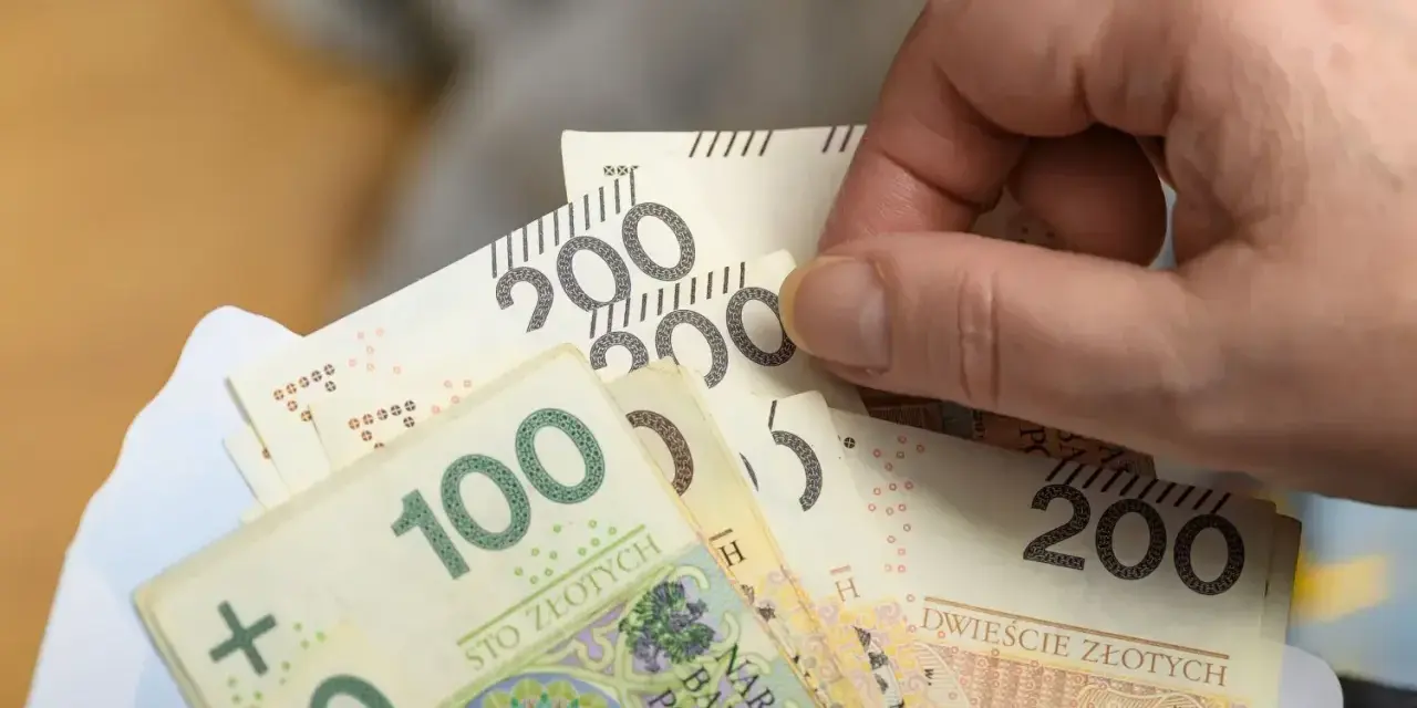 Dłoń trzyma banknoty 100 i 200 zł. Czy to już zapowiedź podwyżki najniższej krajowej 2026?