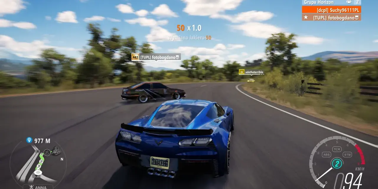 Wyścig w Horizon 3: niebieski Chevrolet Corvette ściga się z innymi autami na krętej drodze.