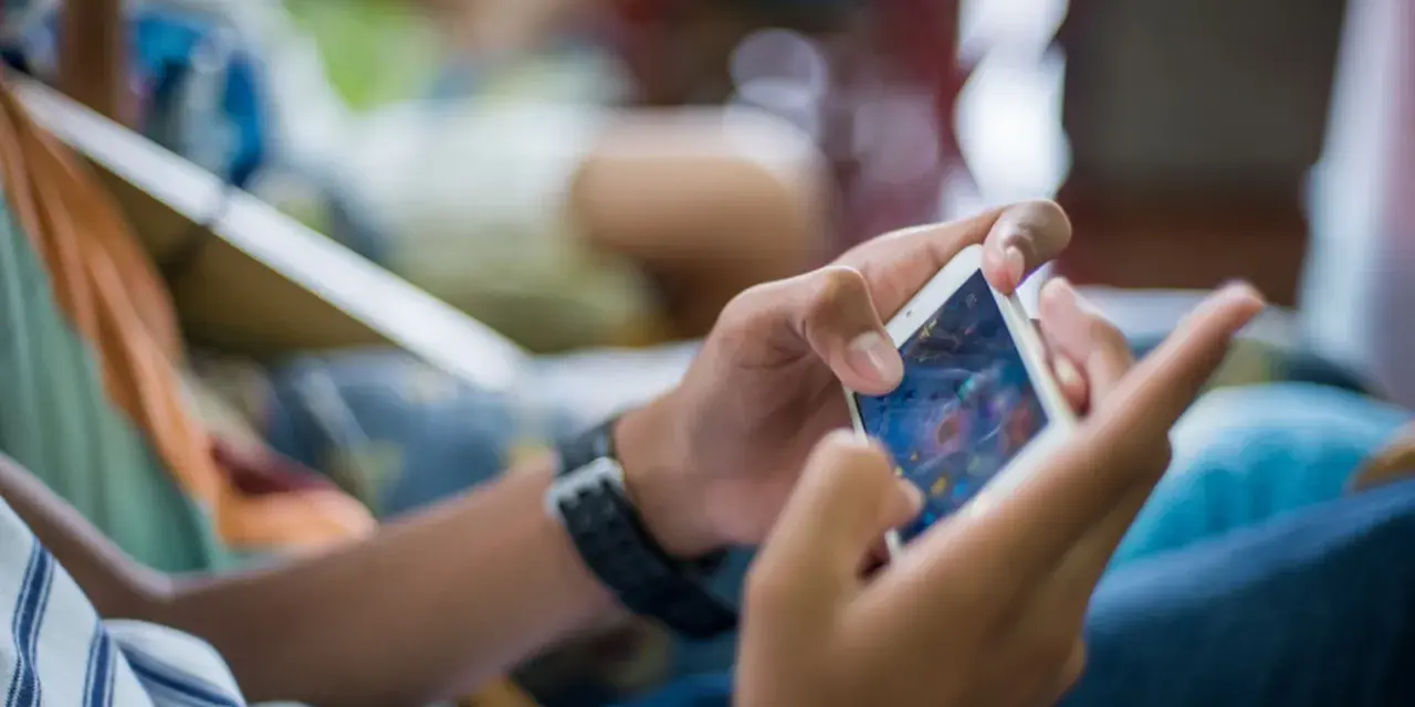 Ręce trzymające smartfon, grające w grę. Czy to przykład phubbing co to znaczy? Ignorowanie otoczenia dla telefonu.
