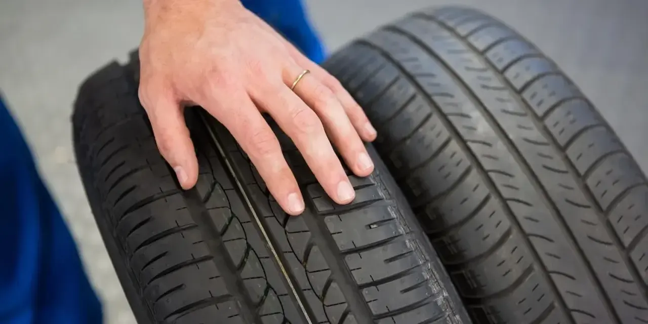 Dłoń mechanika dotyka bieżnika opony Hankook, sprawdzając jej stan. Dobre opony Hankook opinie to podstawa bezpiecznej jazdy.