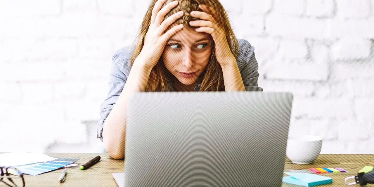 Verzweifelte Frau mit Händen in den Haaren, die auf einen Laptop starrt. Die Website-Migration scheint sie zu überfordern.