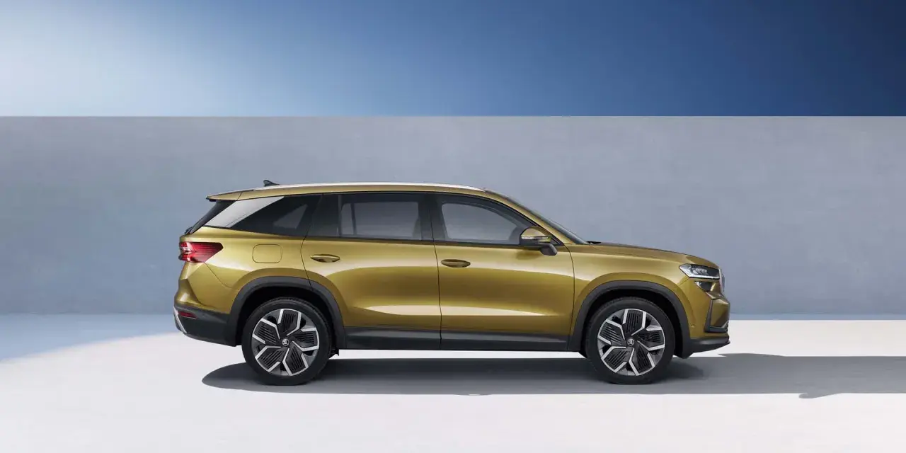 Złoty skoda suv z nowoczesnymi felgami stoi na tle niebieskiego nieba i szarej ściany.