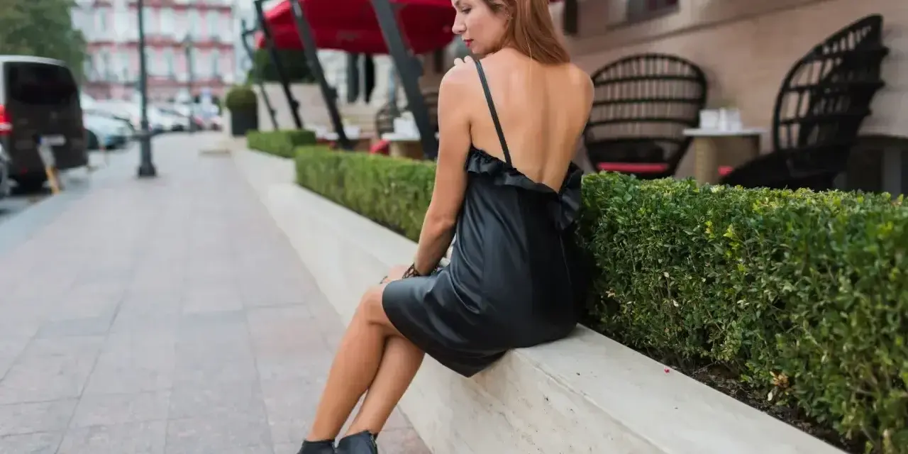 Elegancka kobieta w czarnej sukience i sandałkach na obcasie. Idealne buty do czarnej sukienki na wieczorne wyjście.