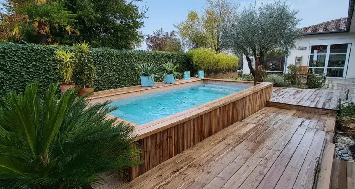 Aménagement abord piscine hors sol en bois, avec terrasse et végétation luxuriante.