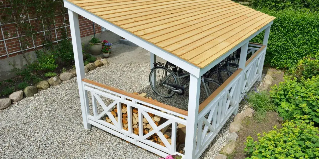 En vit cykelskjul ritning med trätak, som rymmer flera cyklar. Under taket finns även ved.