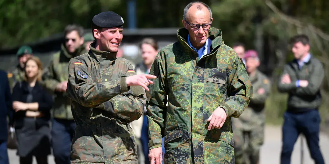 Dwóch mężczyzn w mundurach wojskowych, jeden z flagą Polski, drugi z napisem "MERZ" (Niemcy).