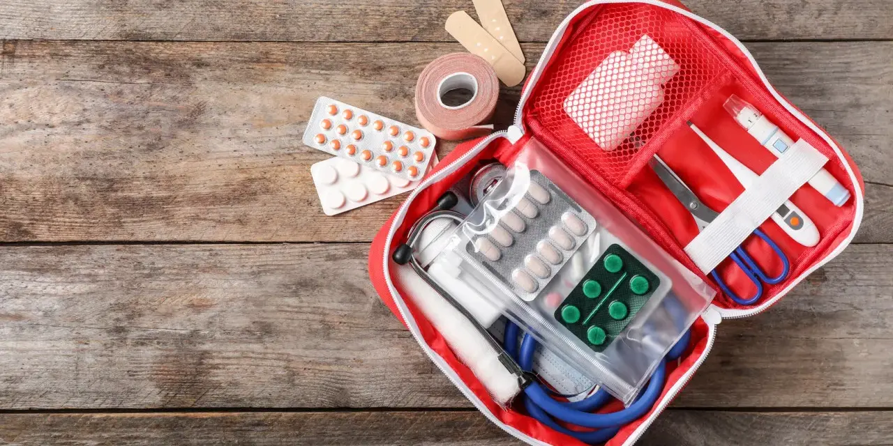 Trousse de secours pharmacie liste : pansements, rouleau de sparadrap, pilules, thermomètre, ciseaux, stéthoscope et masque.