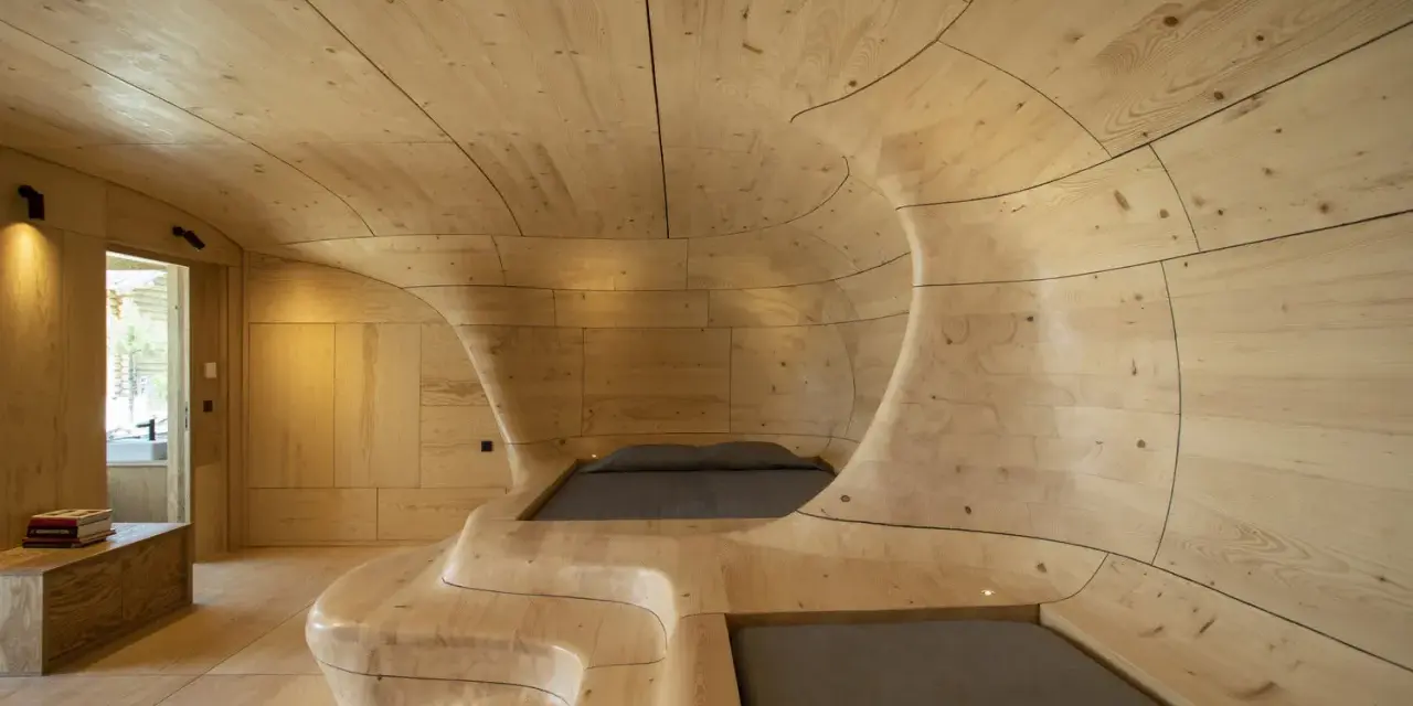 Interior de una casa cueva con paredes y techo de madera curvada, creando un espacio orgánico y acogedor.