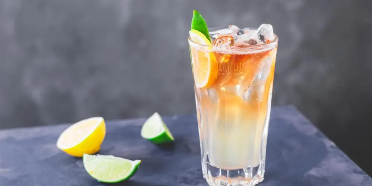 Orzeźwiający drink Long Island Iced Tea z plasterkami cytryny i limonki, idealny na upalne dni.