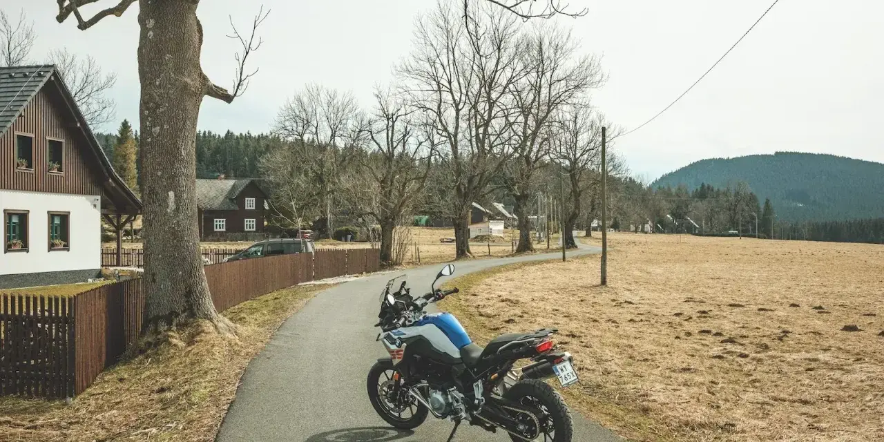 Motocykl czeka na jednodniowy wypad motocyklowy. W tle wiejskie domki i puste pola.