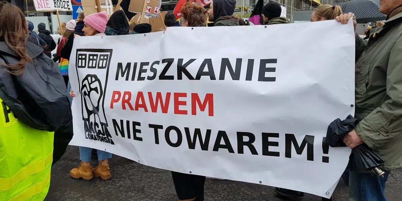 Protestujący niosą transparent "Mieszkanie prawem nie towarem!", domagając się ustaw chroniących lokatorów.
