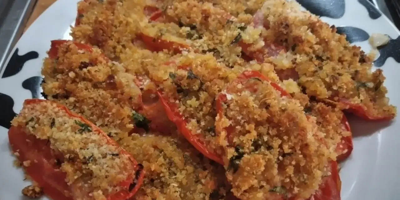 Pomodori gratinati al forno, un piatto semplice e gustoso, con una croccante panatura dorata e erbe aromatiche.