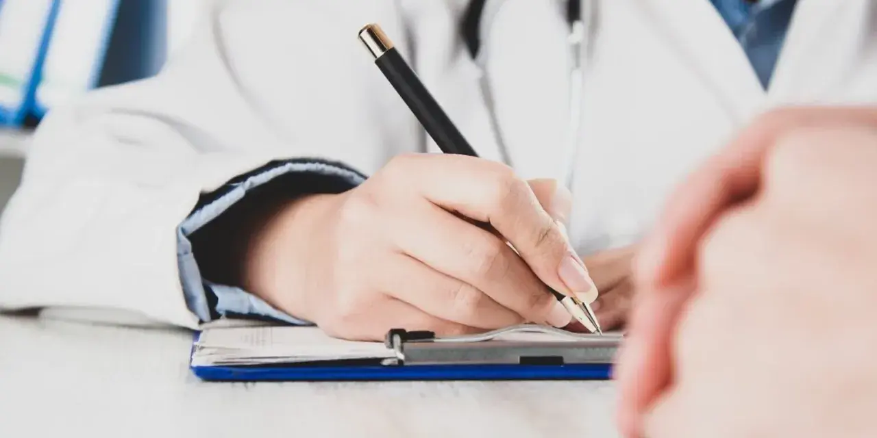 Lekarz pisze receptę, zastanawiając się, czy zwolnienie od psychiatry zostaje w papierach.