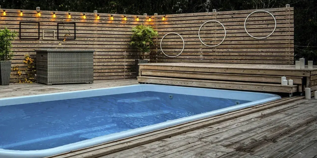 En avkopplande utomhusmiljö med pool och trädäck. En idé för att bygga eget pooltak kan inspireras av den snygga träpanelen och belysningen.