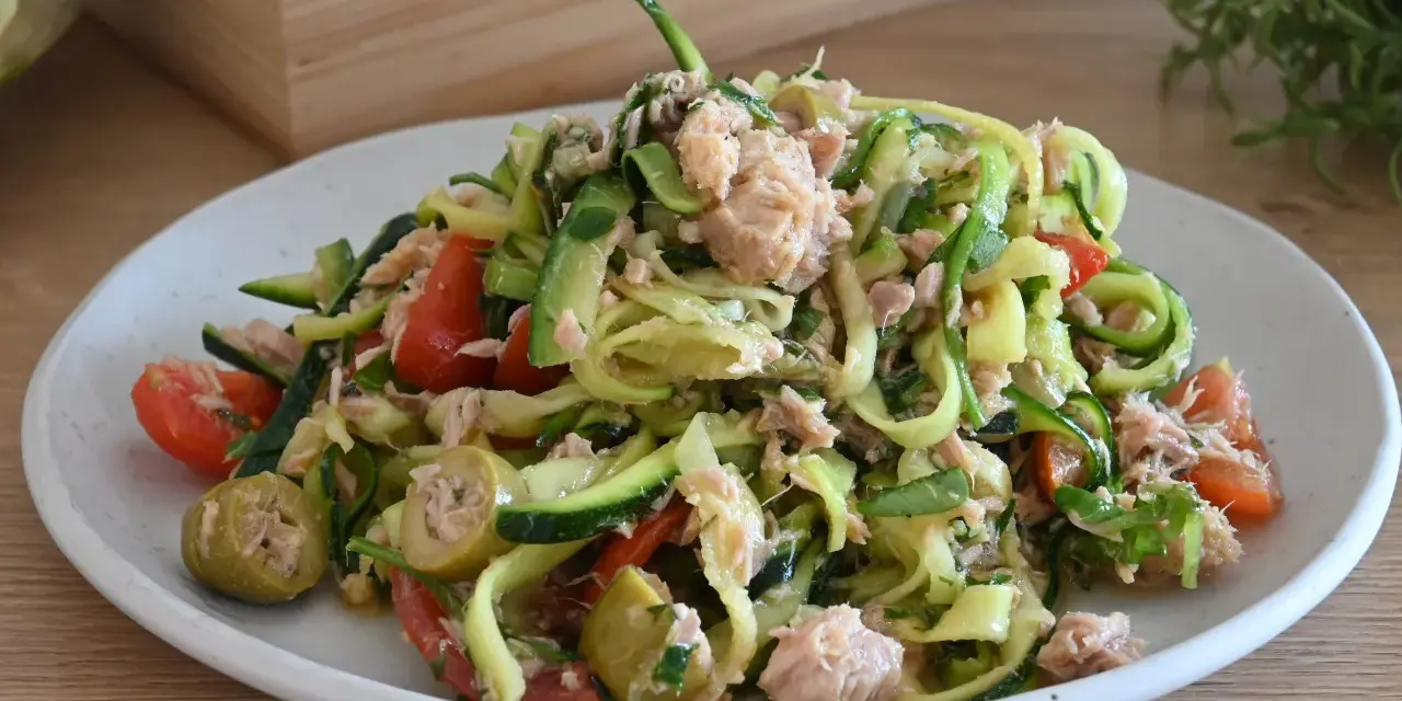Deliziosa insalata di zucchine a spirale con tonno, pomodorini e olive verdi, un piatto fresco e leggero.