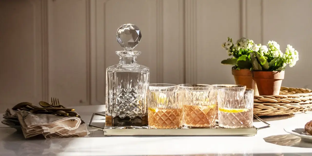 Elegancka karafka i szklanki z drinkami, idealne do degustacji whisky. Z czym pić whisky? Z cytryną i lodem, w dobrym towarzystwie.