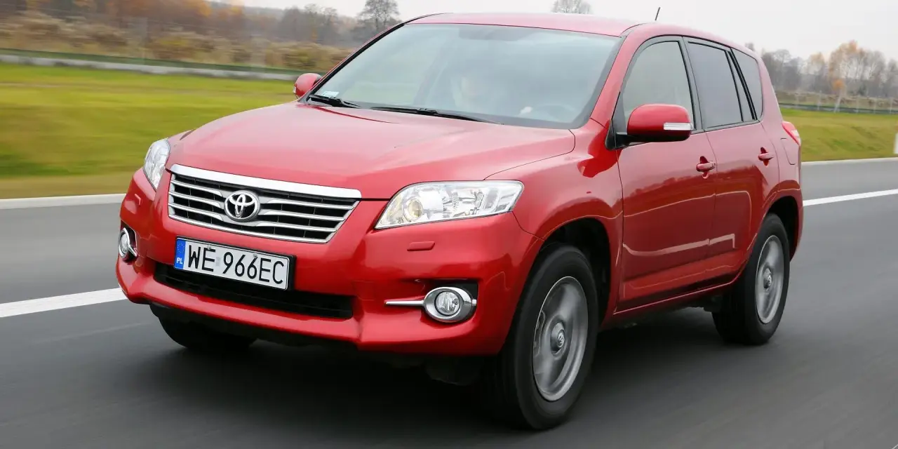Czerwony SUV do 30 tys. na drodze, z widocznym grillem i tablicą rejestracyjną WE 966EC.
