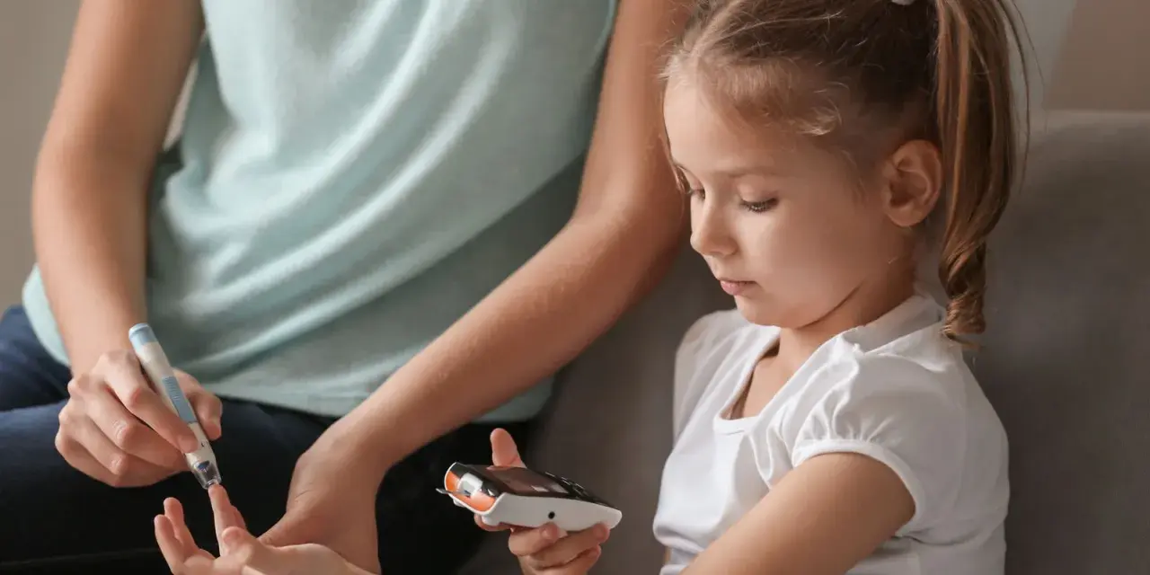 Mutter hilft Kind bei Blutzuckermessung. Ein wichtiger Teil im Leben mit diabetes kinder.