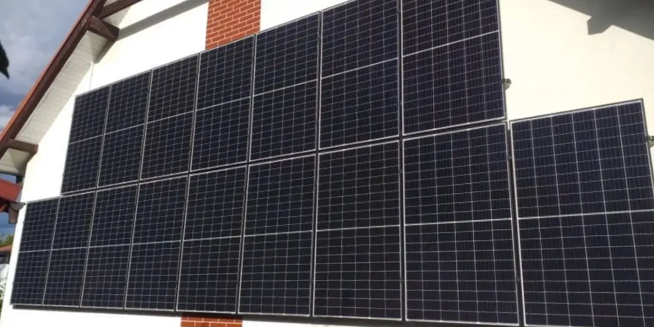 Duży zestaw paneli fotowoltaicznych na pionowej ścianie domu, zbierający energię słoneczną.