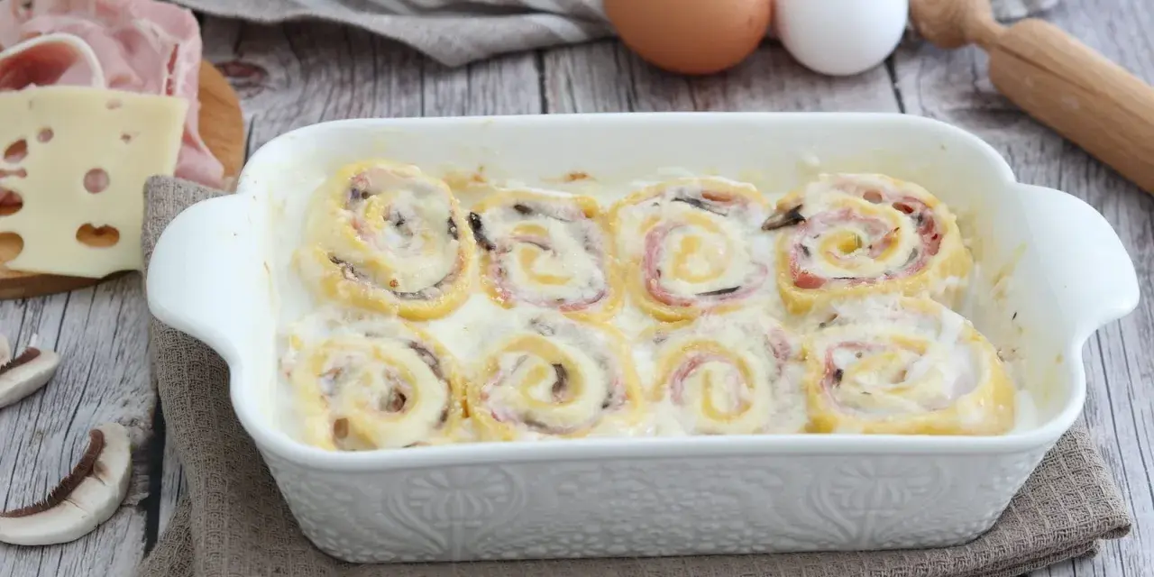 Nidi di rondine in una teglia bianca, con prosciutto, formaggio e funghi. Ingredienti per un piatto delizioso.