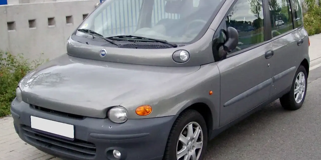 Szary Fiat Multipla, często uznawany za najbrzydsze auto na świecie, stoi na ulicy. Jego nietypowy kształt przyciąga wzrok.
