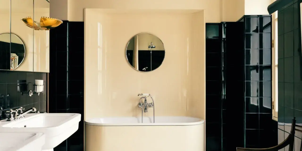 Élégante salle de bain noir et blanc avec baignoire îlot, lavabo double vasque et carrelage brillant.