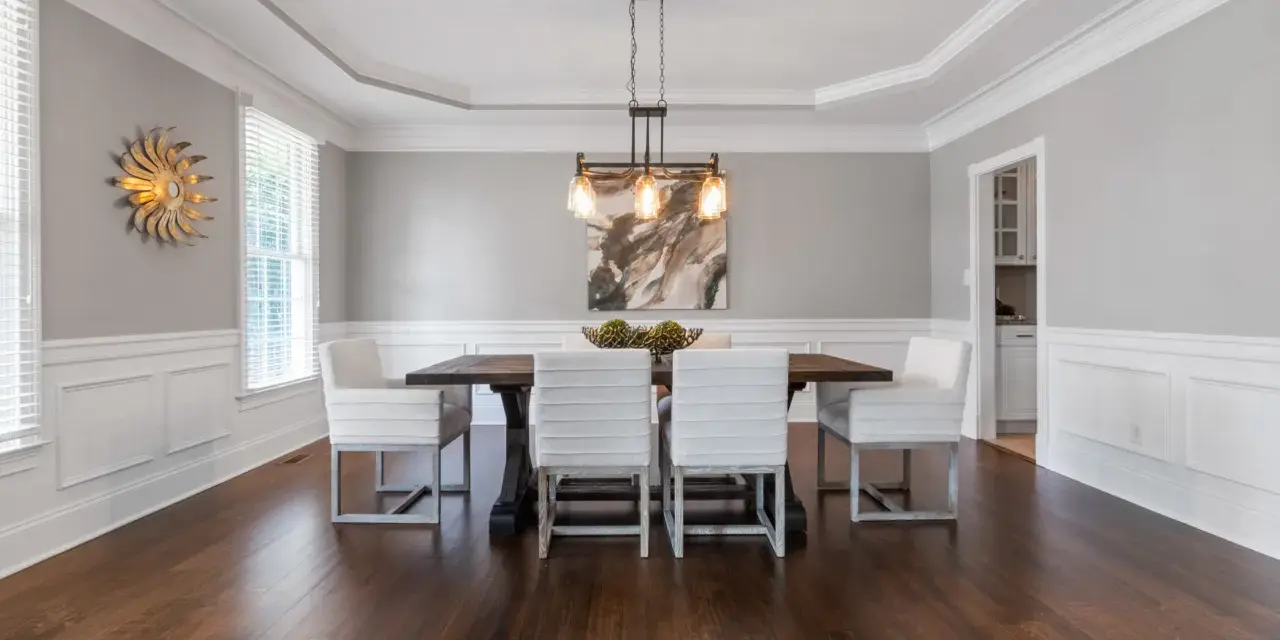 Comedor elegante con paredes y techo pintados del mismo color gris claro, creando un ambiente sereno.