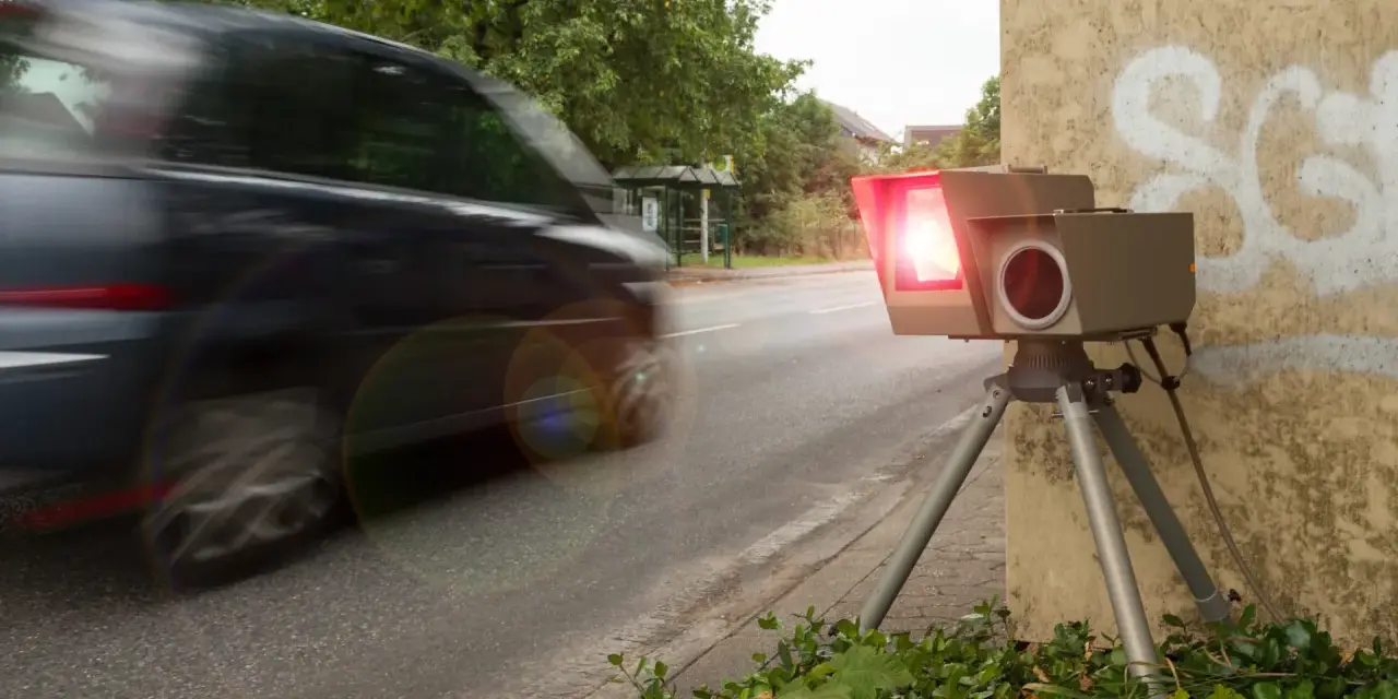 Ein Blitzer, der gerade ein Auto fotografiert, wie sehen Blitzer ohne Blitz aus? Dieses Gerät steht am Straßenrand, bereit für Geschwindigkeitsünder.