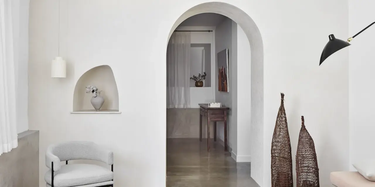 Un salon moderne avec un arche en pierre, un fauteuil gris, des lampes noires et un habillage arche maison.