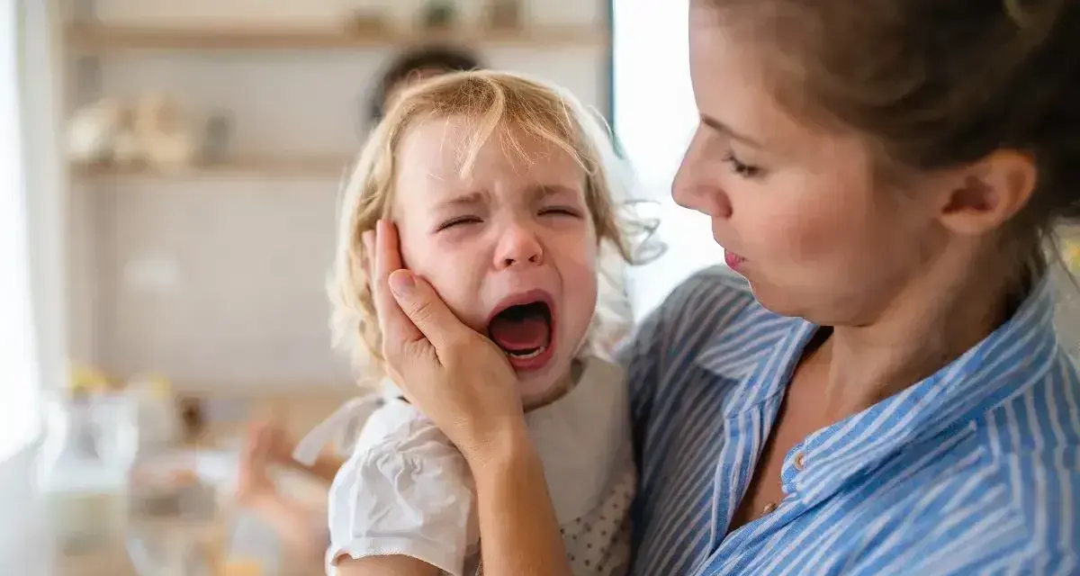 Mama próbuje uspokoić płaczące dziecko, które głośno krzyczy.