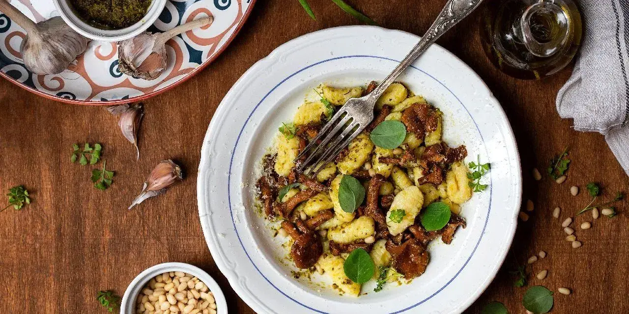 Szybkie danie z gnocchi z grzybami i pesto, posypane orzeszkami pinii. Idealne na szybki obiad.